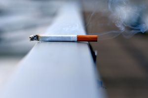 a burning cigarette sitting on a ledge