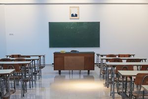 an empty classroom with a blackboard and a few chairs